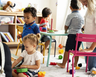 Nursery children playing with teacher