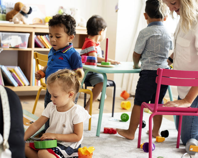 Nursery children playing with teacher