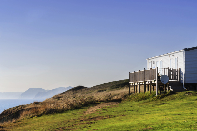 Static caravan on a clifftop with a wooden deck overlooking the sea on a clear day