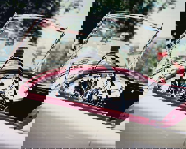 A vintage MG convertible with highlighting its aged condition, set against vineyards and rolling hills.