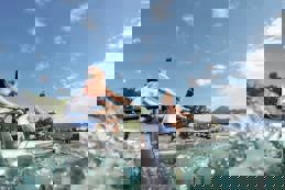 Two female athletes rowing lake