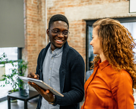Co-workers smiling as they discuss something on a tablet device