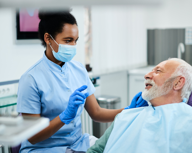 Dental nurse communicating with senior patient