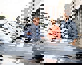 Latin American salesman showing a car to a couple 