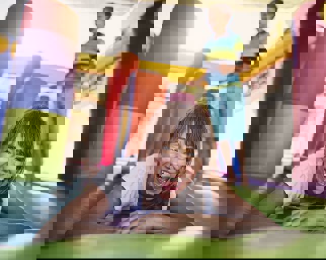 Boy and girl having fun jumping in inflatable castle playground.